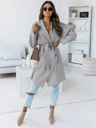NEWYORKLISTED STYLE COLLECTION: Woman wearing a gray coat in a modern living room