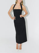 NEWYORKLISTED STYLE COLLECTION: Woman wearing a black halter neck dress against a white background