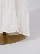 NEWYORKLISTED STYLE COLLECTION: White sheer fabric draped over a gold circular object on a white background