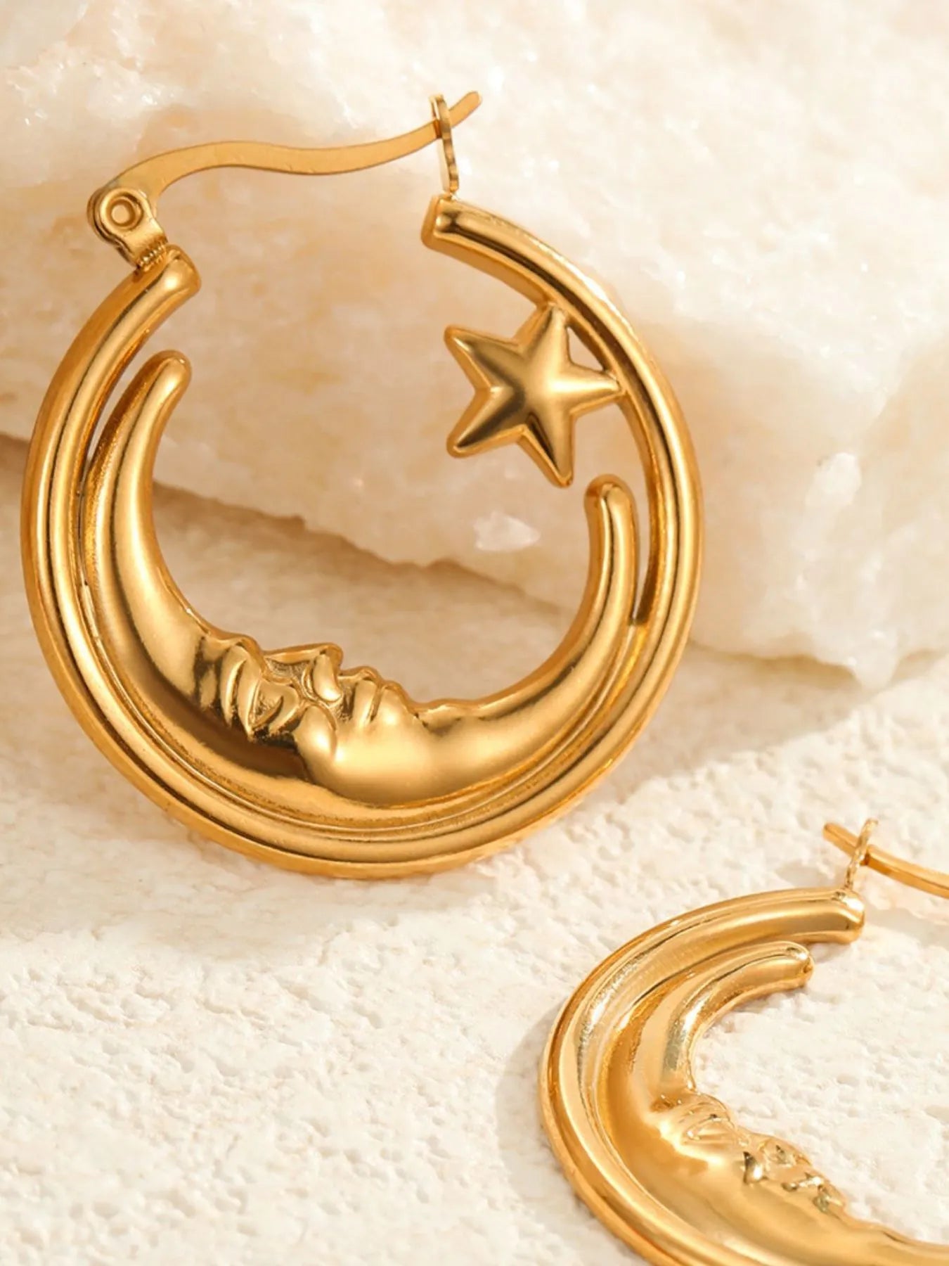 Gold hoop earrings with moon and star design on a textured beige surface- NEWYORKLISTED STYLE COLLECTION 
