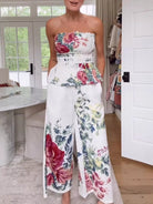 NEWYORKLISTED STYLE COLLECTION: Woman wearing a strapless floral top and wide-leg pants in a room with a desk and door.