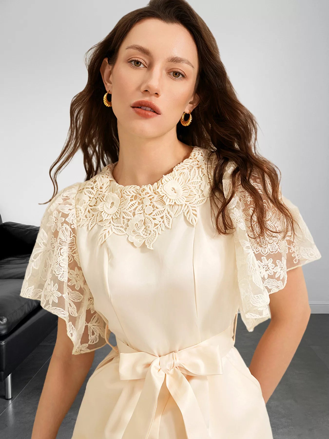 NEWYORKLISTED STYLE COLLECTION: Woman wearing a beige lace dress with a bow tie in a neutral setting