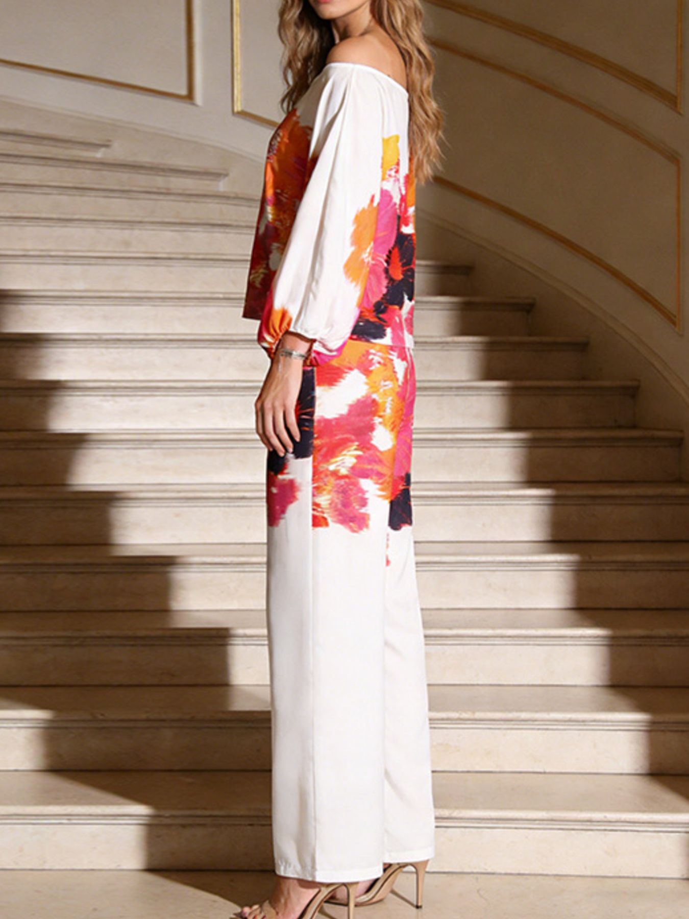 NEWYORKLSITED STYLE COLLECTION: Woman wearing a colorful off-shoulder dress standing on a staircase.