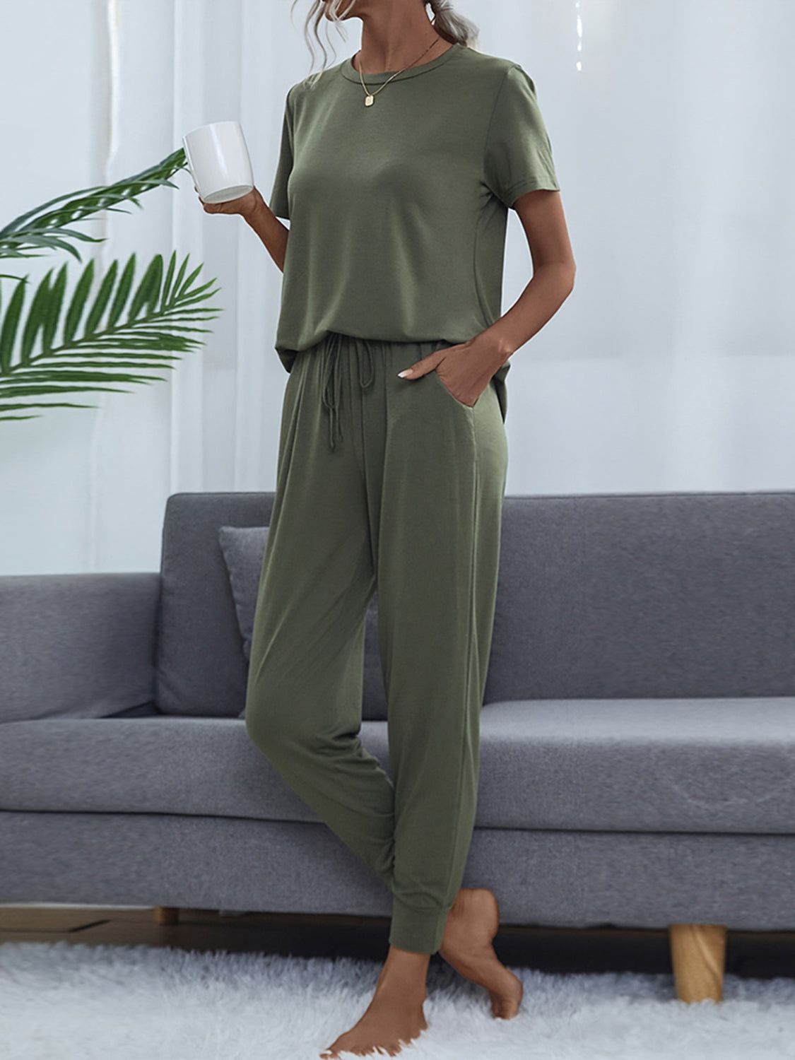 NEWYORKLISTED Intimate Apparel: Person wearing a green pajama set sitting on a gray couch.