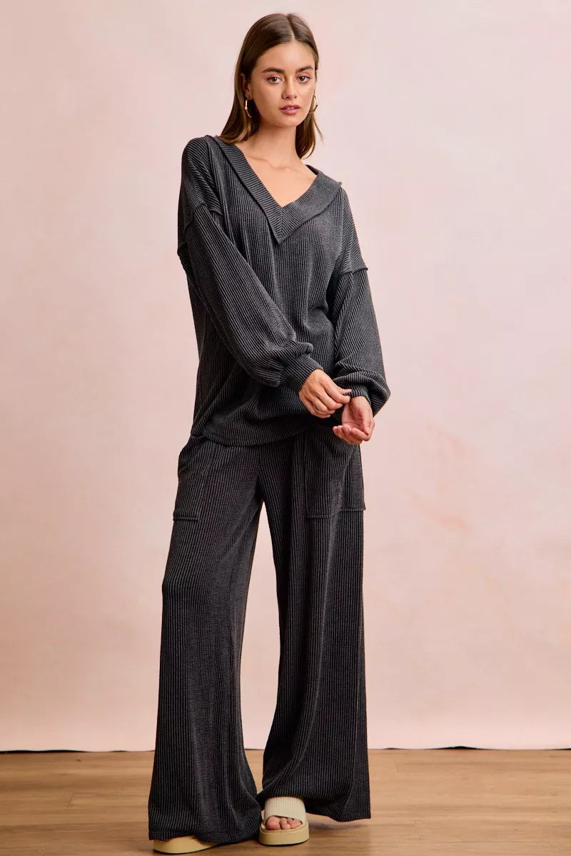 NEWYORKLISTED Comfort Collection: Woman wearing a dark gray outfit with wide-leg pants against a plain background