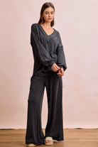 NEWYORKLISTED Comfort Collection: Woman wearing a dark gray outfit with wide-leg pants against a plain background