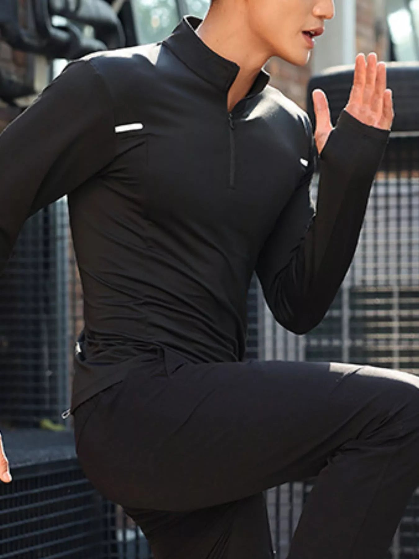 NEWYORKLISTED ATLAS MEN'S COLLECTION: Person wearing a black athletic outfit with a white logo, sitting on a bench.