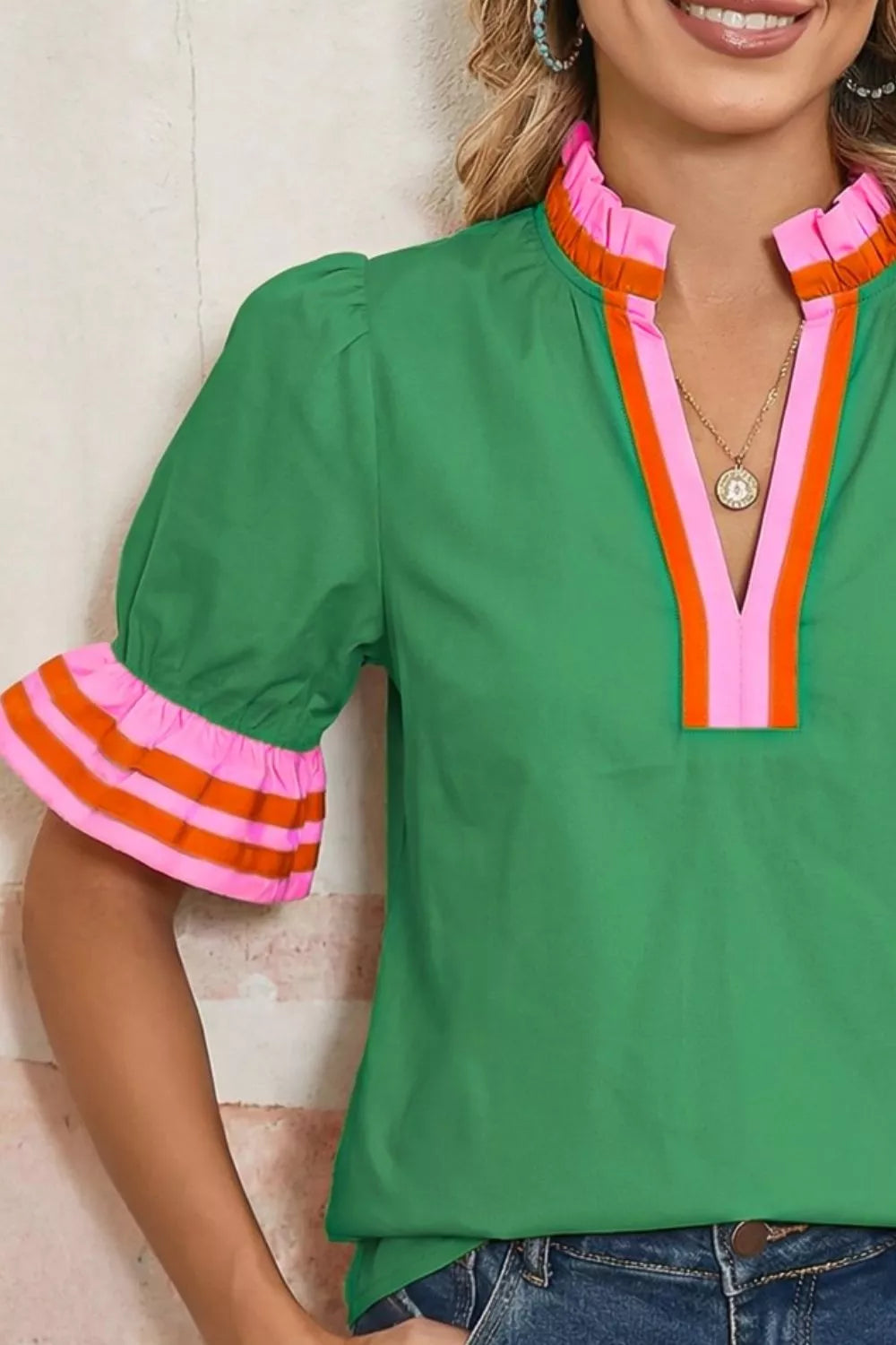 NEWYORKLISTED STYLE COLLECTION: Green blouse with colorful trim worn by a person, against a neutral background