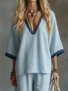 NEWYORKLISTED STYLE COLLECTION: Woman wearing a light blue outfit with a deep neckline against a neutral background