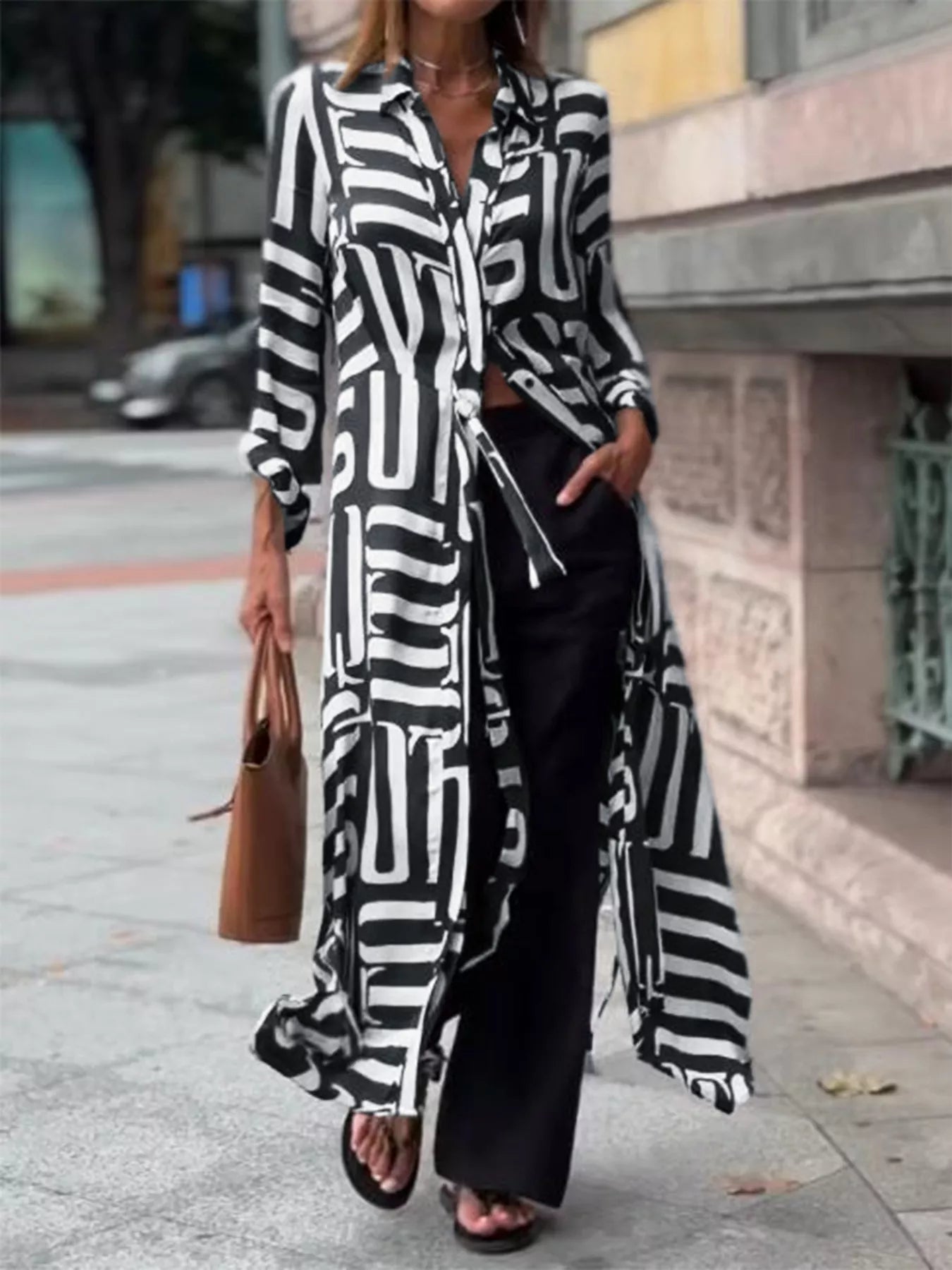 NEWYORKLISTED STYLE COLLECTION: Person wearing a long black and white patterned shirt with black pants on a city street.