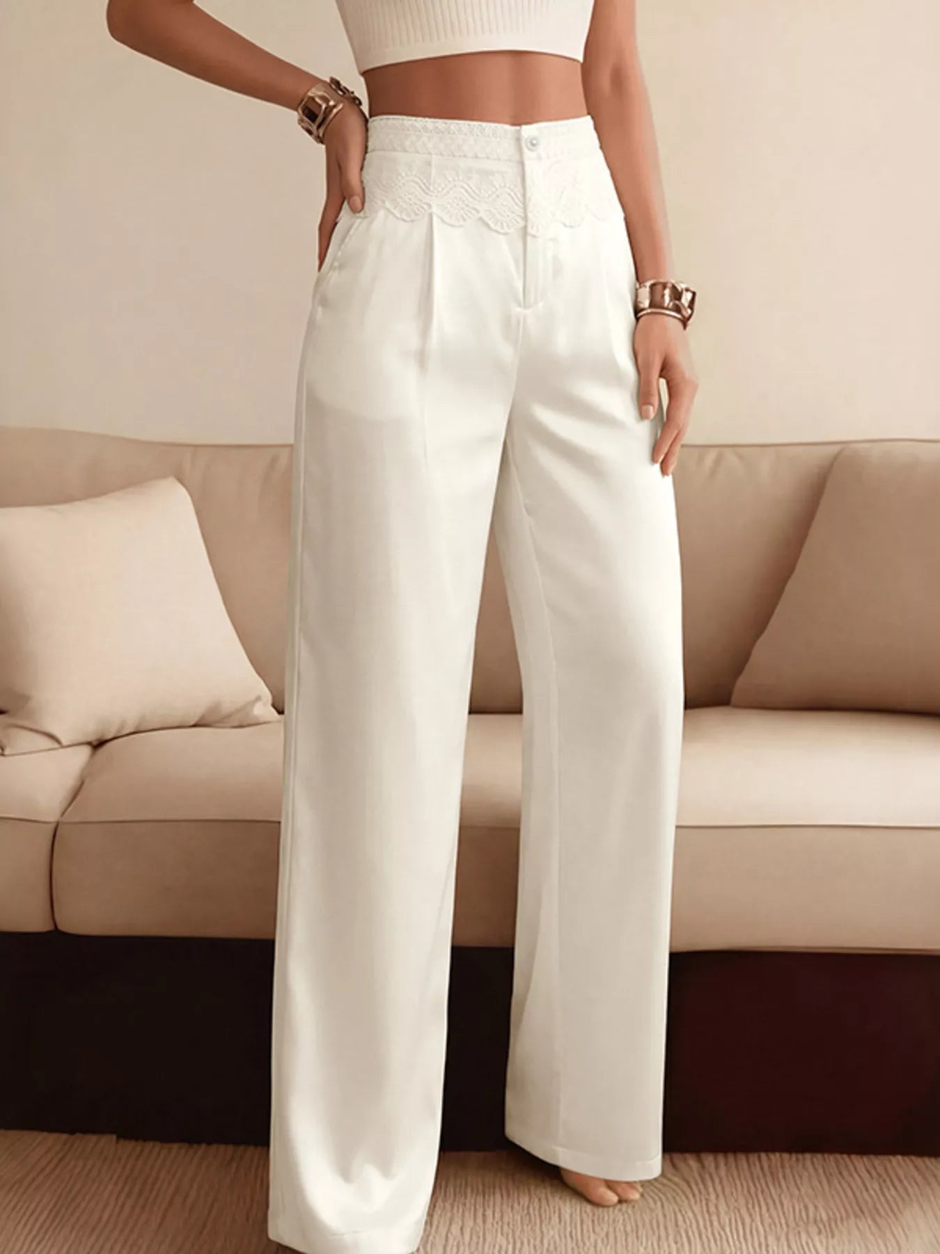 NEWYORKLISTED STYLE COLLECTION: Person wearing white pants standing in a room with a beige couch.