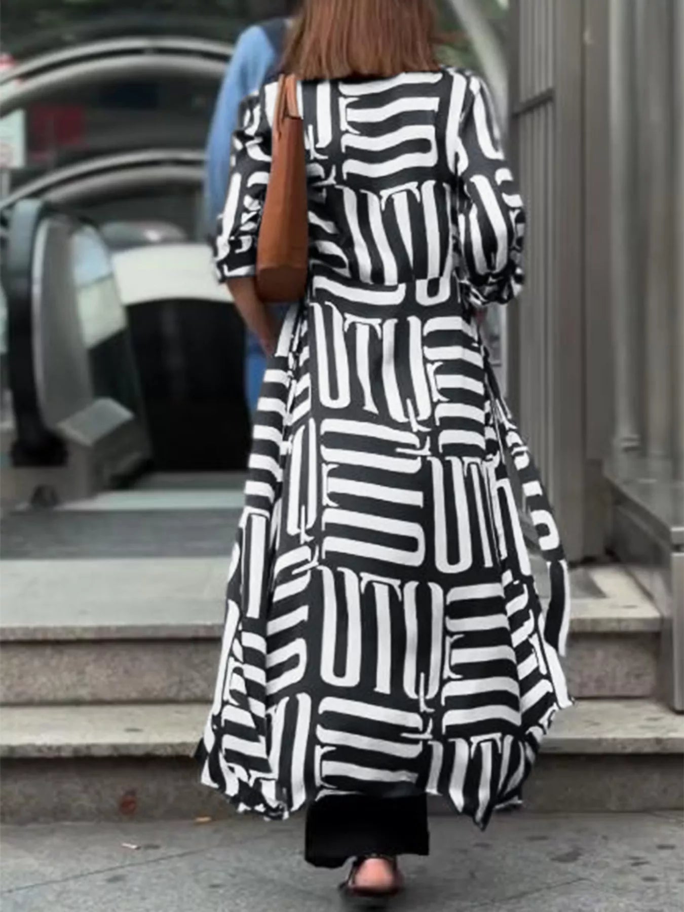 NEWYORKLISTED STYLE COLLECTION: Person wearing a black and white patterned dress walking outdoors.
