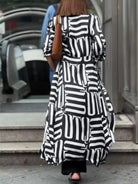NEWYORKLISTED STYLE COLLECTION: Person wearing a black and white patterned dress walking outdoors.
