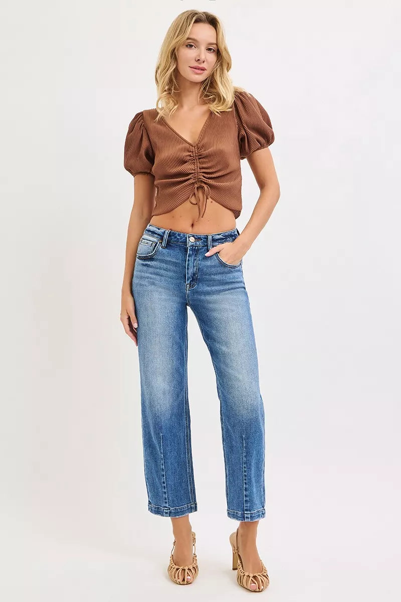 NEWYORKLISTED DENIM COLLECTION: Woman wearing a brown top and blue jeans on a white background