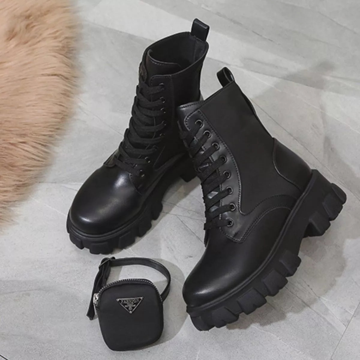 NEWYORKLISTED SHOE COLLECTION: Pair of black leather boots with a small black Prada bag on a light wooden floor.