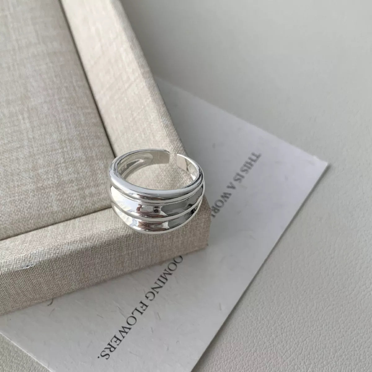 NYLD Glamour Collection: Silver ring on a textured surface with text in the background