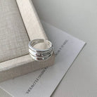 NYLD Glamour Collection: Silver ring on a textured surface with text in the background