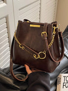 Brown handbag with gold accents held by a person against a neutral background New York Listed Style Collection 