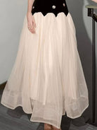 NEWYORKLISTED STYLE COLLECTION: Beige tulle skirt worn over a black top against a gray background