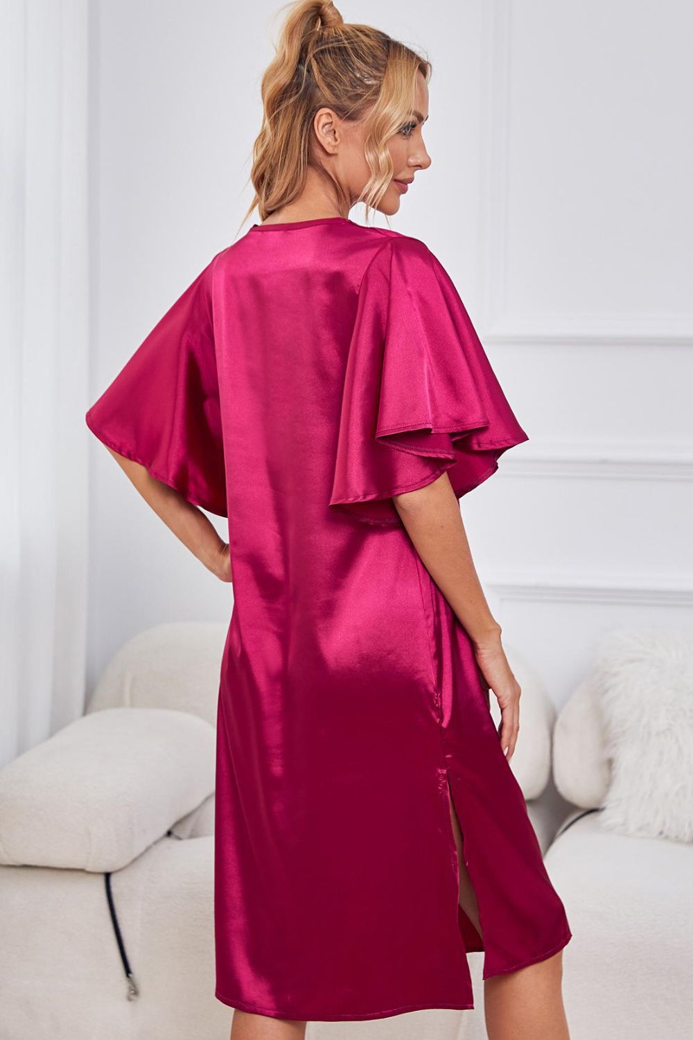NEWYORKLISTED Intimate Apparel: Woman wearing a magenta satin dress with ruffled sleeves in a minimalistic room.