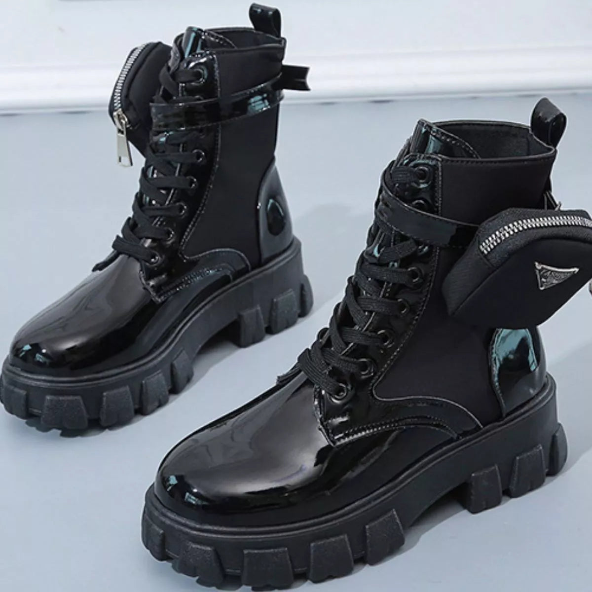 NEWYORKLISTED SHOE COLLECTION: Black glossy combat boots with thick soles on a light gray background