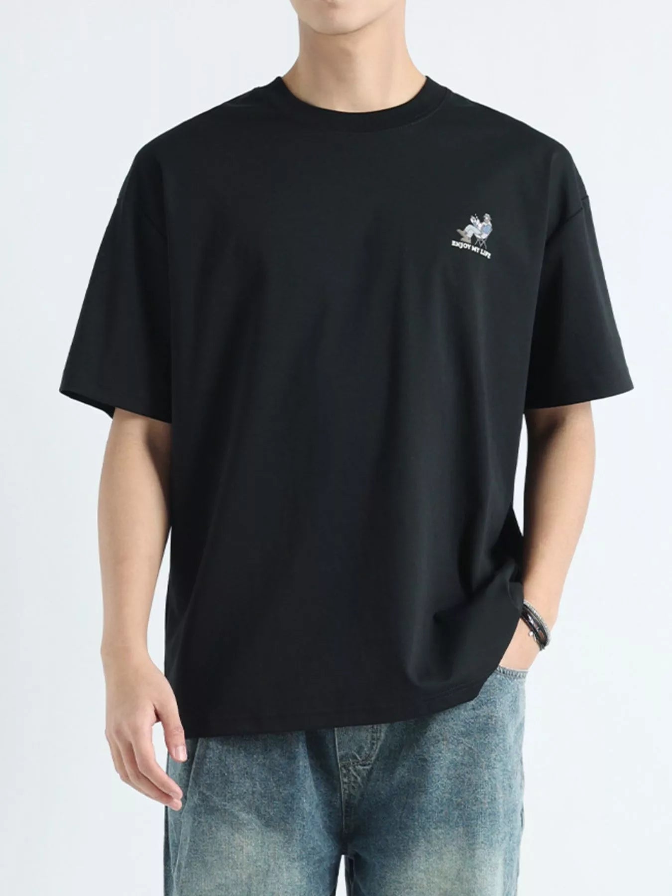 Person wearing a black t-shirt with a small logo on a white background