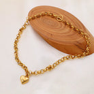 NYLD Glamour Collection by NEWYORKLISTED: Gold chain bracelet with a heart charm on a wooden block