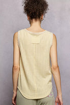NEWYORKLISTED STYLE COLLECTION: Woman wearing a light yellow sleeveless top against a gray background