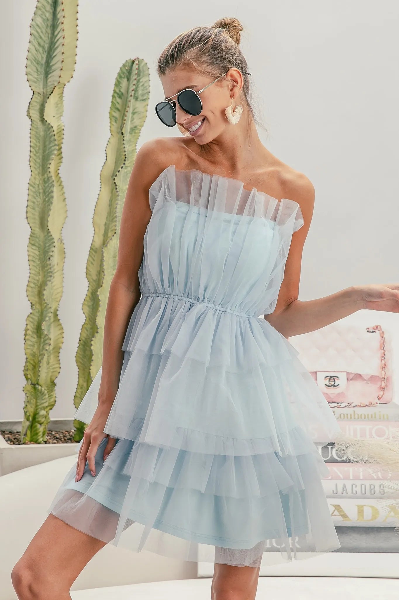 NEWYORKLISTED STYLE COLLECTION: Sleeveless Layered Organza Dress Woman wearing a light blue strapless dress with sunglasses, standing in front of a cactus plant.