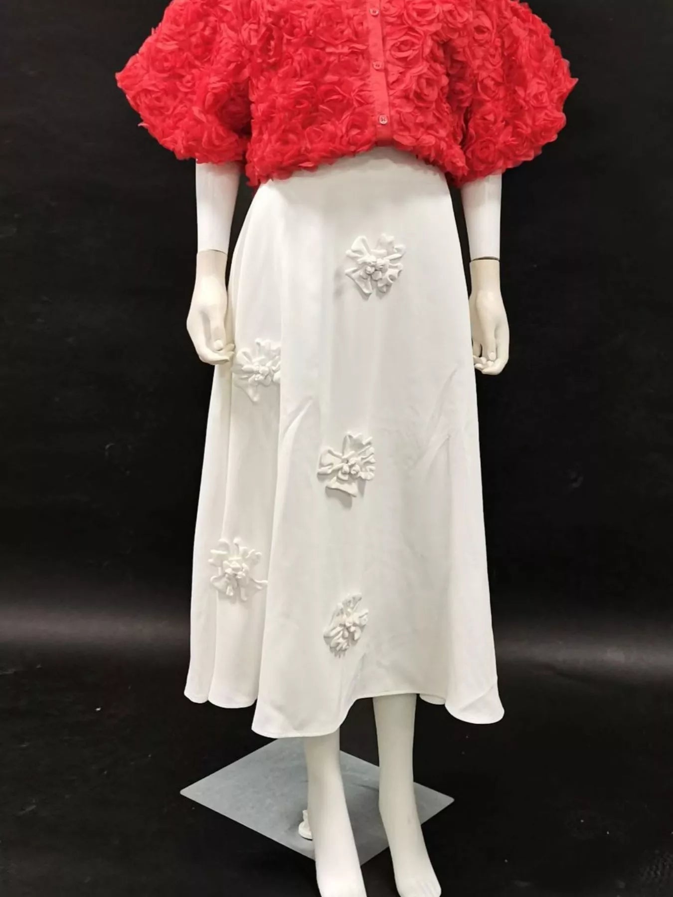 NEWYORKLISTED STYLE COLLECTION: Mannequin wearing a red floral top and white skirt with floral embellishments on a black background