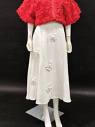 NEWYORKLISTED STYLE COLLECTION: Mannequin wearing a red floral top and white skirt with floral embellishments on a black background
