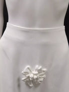 NEWYORKLISTED STYLE COLLECTION: White dress with a decorative floral brooch on a black background