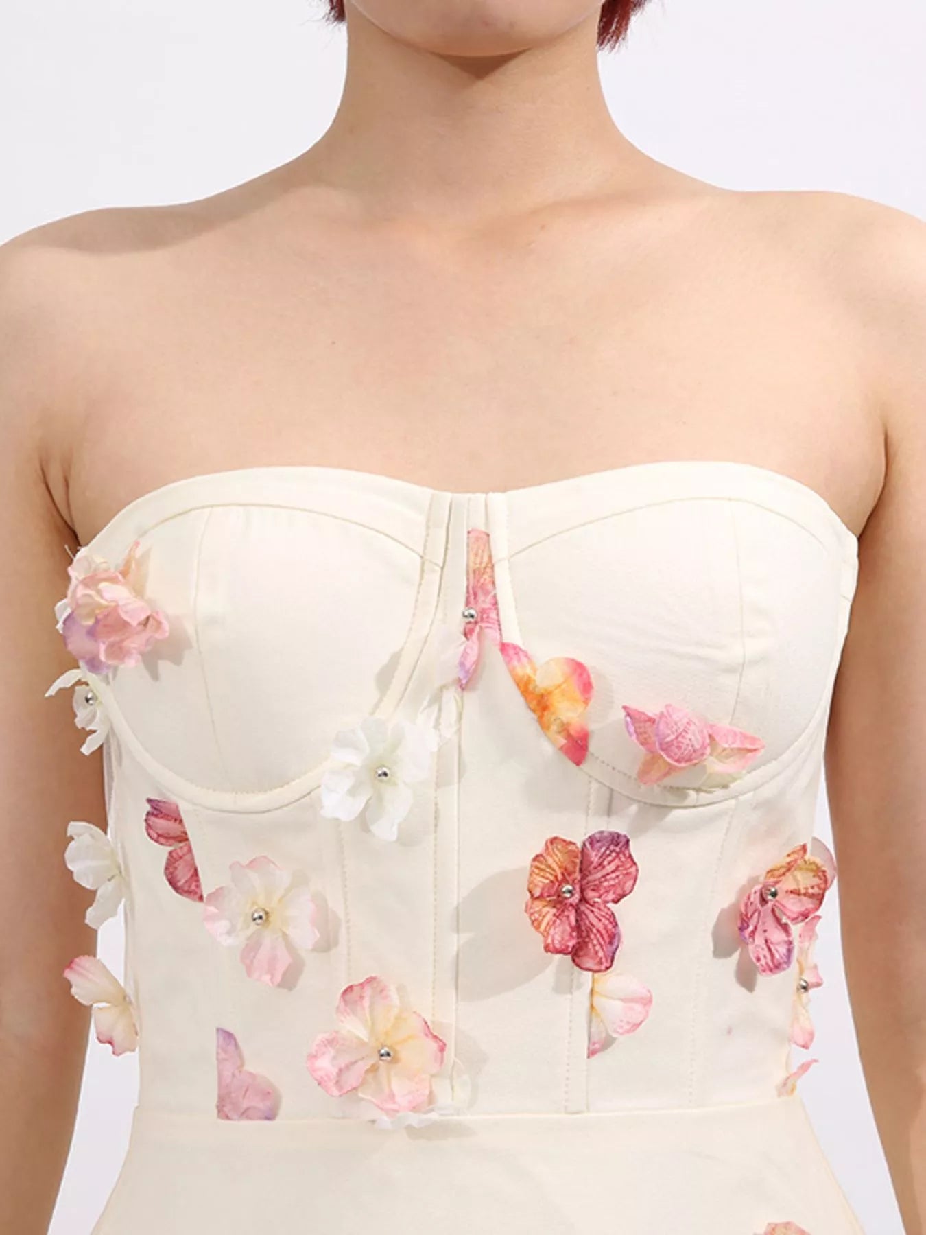 NEWYORKLISTED STYLE COLLECTION: White strapless top with floral embellishments on a plain background