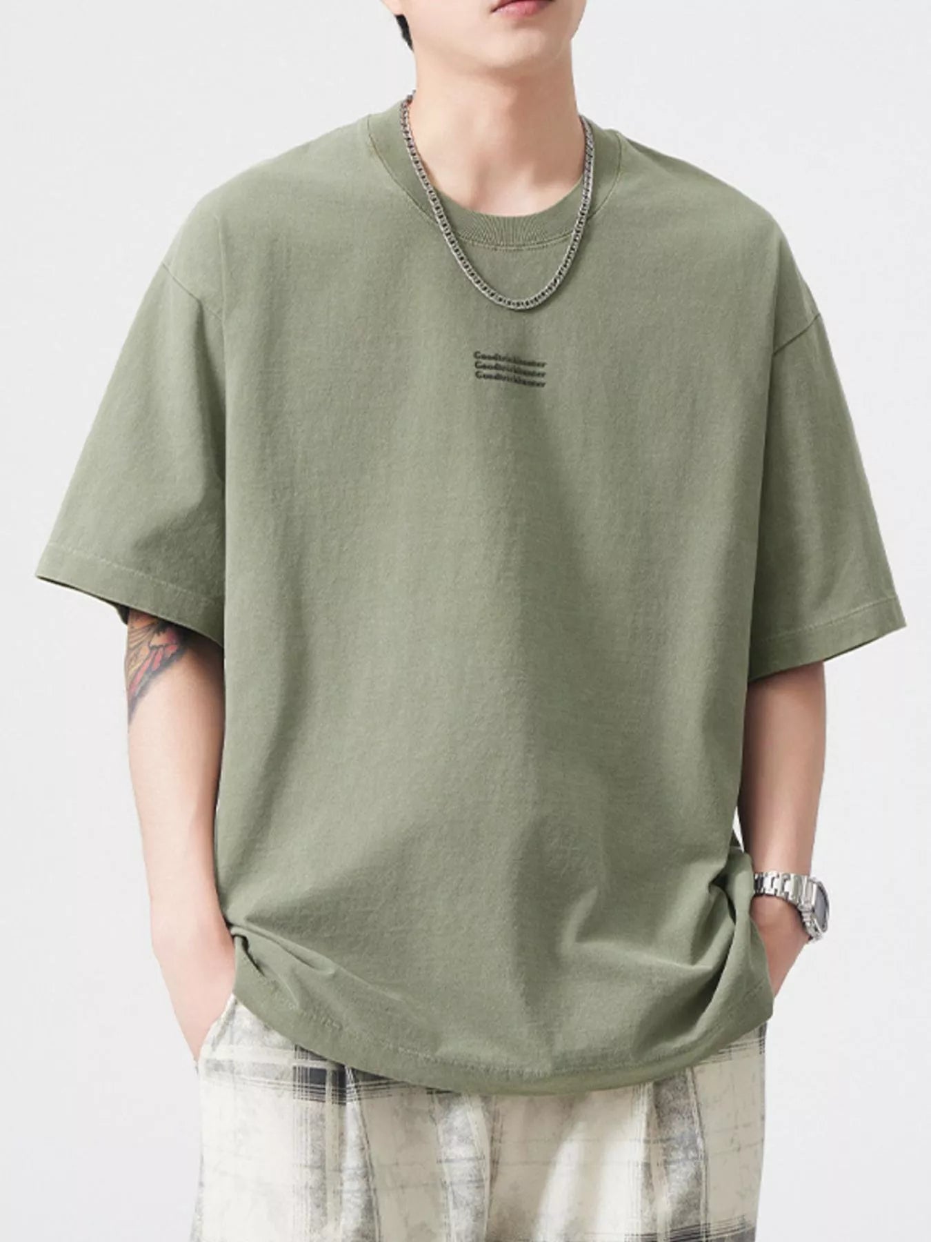NEWYORKLISTED ATLAS MEN's COLLECTION: Person wearing an olive green t-shirt with a small logo on a white background