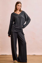 NEWYORKLISTED Comfort Collection: Woman wearing a dark gray outfit with wide-leg pants against a plain background