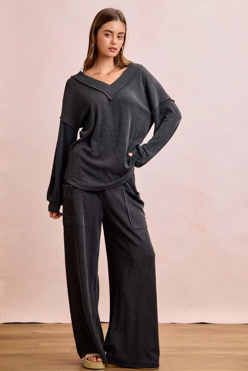 NEWYORKLISTED Comfort Collection: Woman wearing a dark gray outfit with wide-leg pants against a plain background