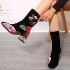 NEWYORKLISTED Shoe Collection: Black socks with floral embroidery being worn on a light wooden floor.