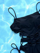 NEWYORKLISTED Eden Collection: Black swimsuit with ruched details on a blue water background