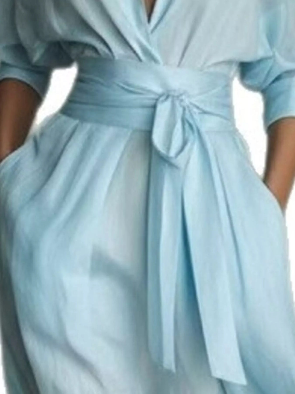 NEWYORKLISTED STYLE COLLECTION: A close-up of a light blue wrap dress with a matching fabric tie belt at the waist, worn by a model.