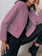 NEWYORKLISTED Style Collection Person wearing a pink jacket with gold buttons and dark jeans against a light background