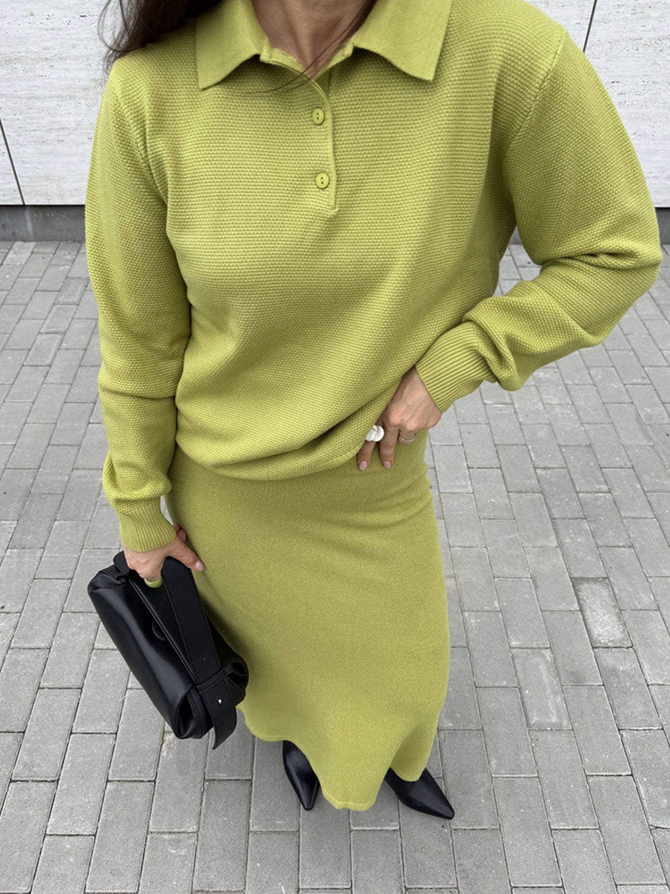 NEWYORKLISTED Comfort Collection: Person wearing a green outfit with a skirt and sweater on a tiled pavement.