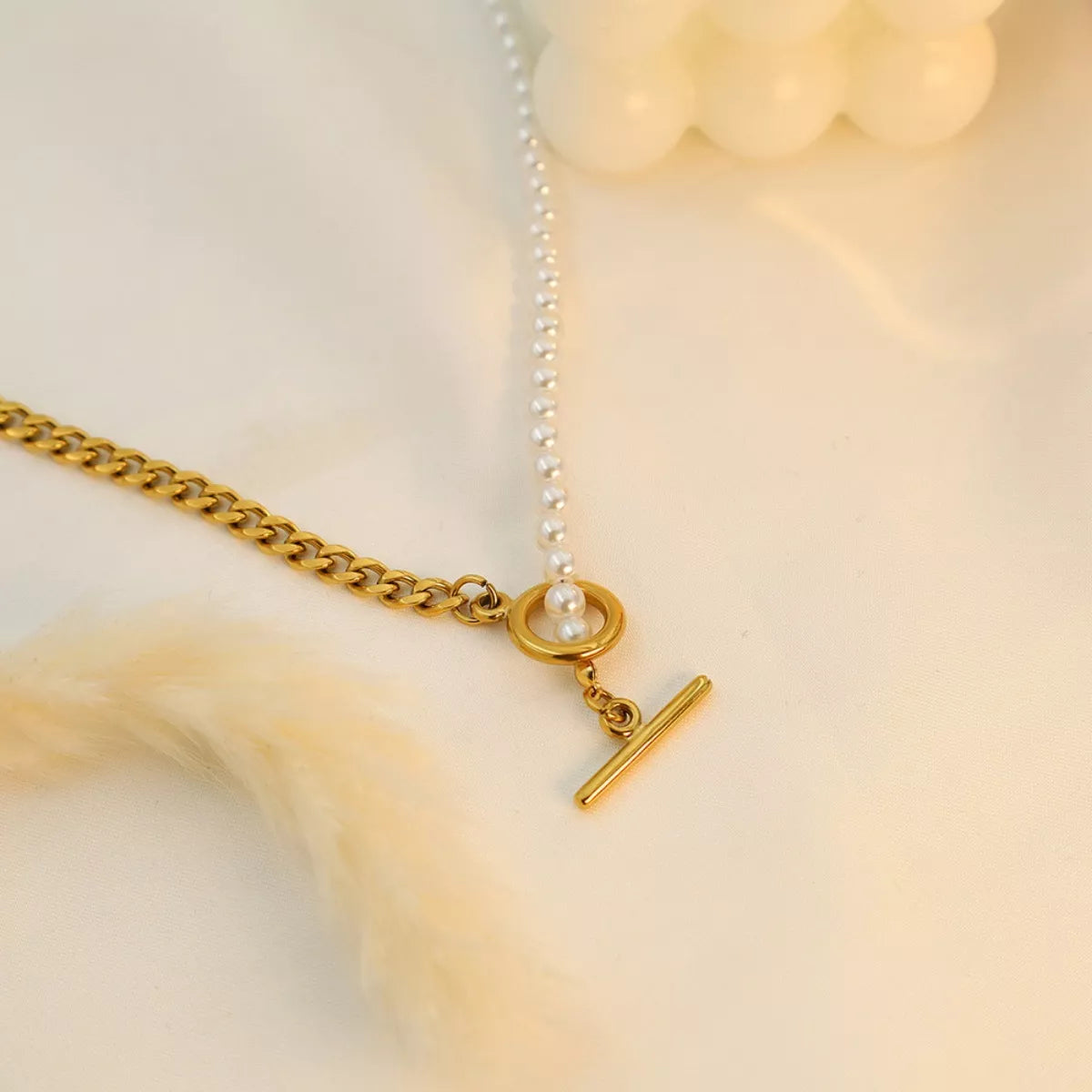 NYLD Glamour Collection by NEWYORKLISTED: Gold necklace with a chain and clasp on a soft beige background