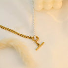 NYLD Glamour Collection by NEWYORKLISTED: Gold necklace with a chain and clasp on a soft beige background