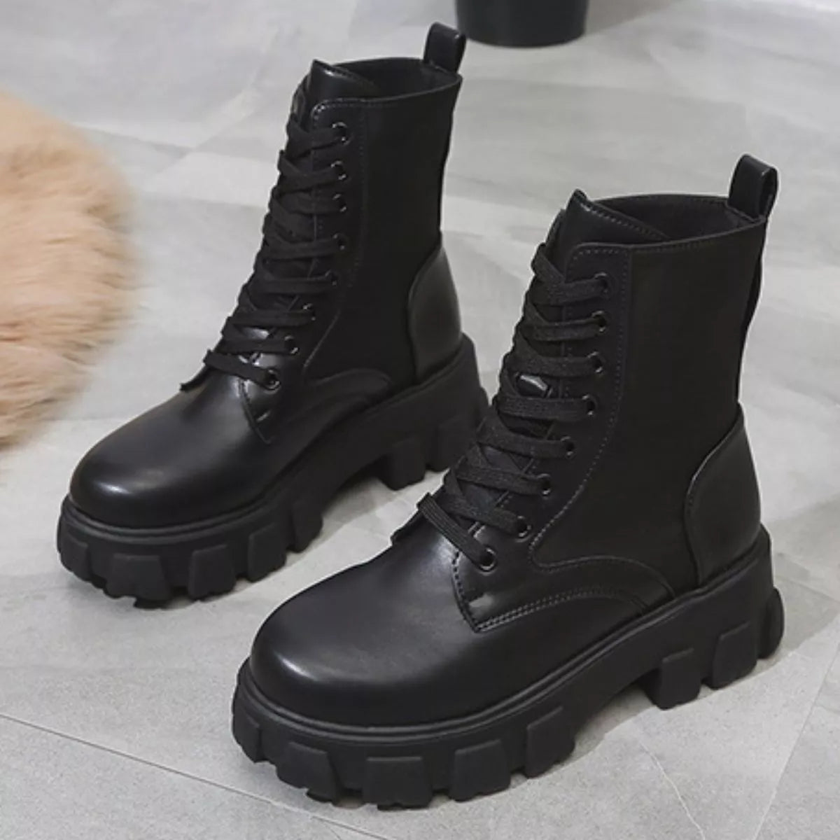 NEWYORKLISTED SHOE COLLECTION: Pair of black leather boots with thick soles on a light gray surface.
