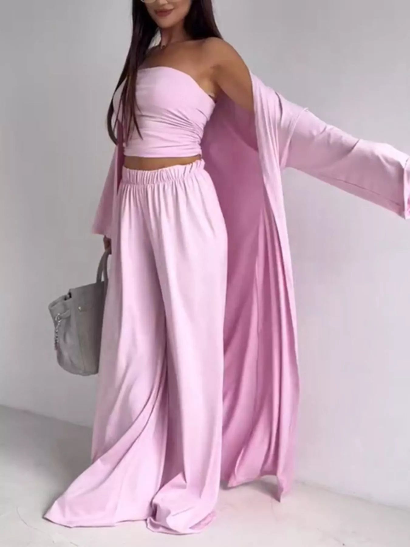 NEWYORKLISTED COMFORT COLLECTION: Woman wearing a pink outfit with a draped fabric over one shoulder against a white background