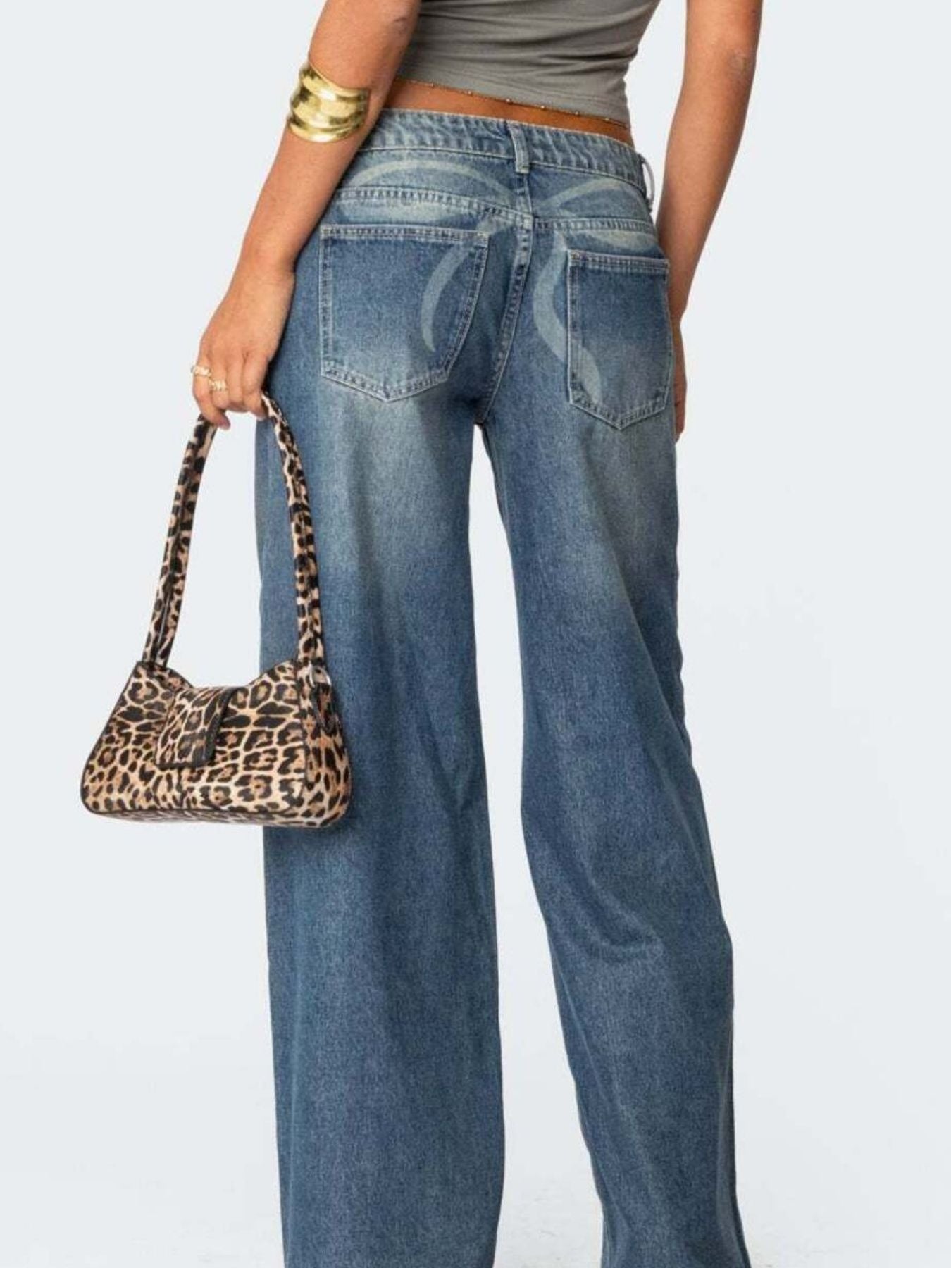 NEWYORKLISTED STYLE COLLECTION: Person wearing blue jeans holding a leopard print handbag on a plain background