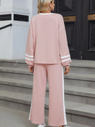 NEWYORKLISTED Comfort Collection: Person wearing a pink tracksuit with white stripes standing on steps.
