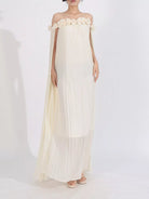 NEWYORKLISTED STYLE COLLECTION: Woman wearing a white off-shoulder dress with floral details on a white background