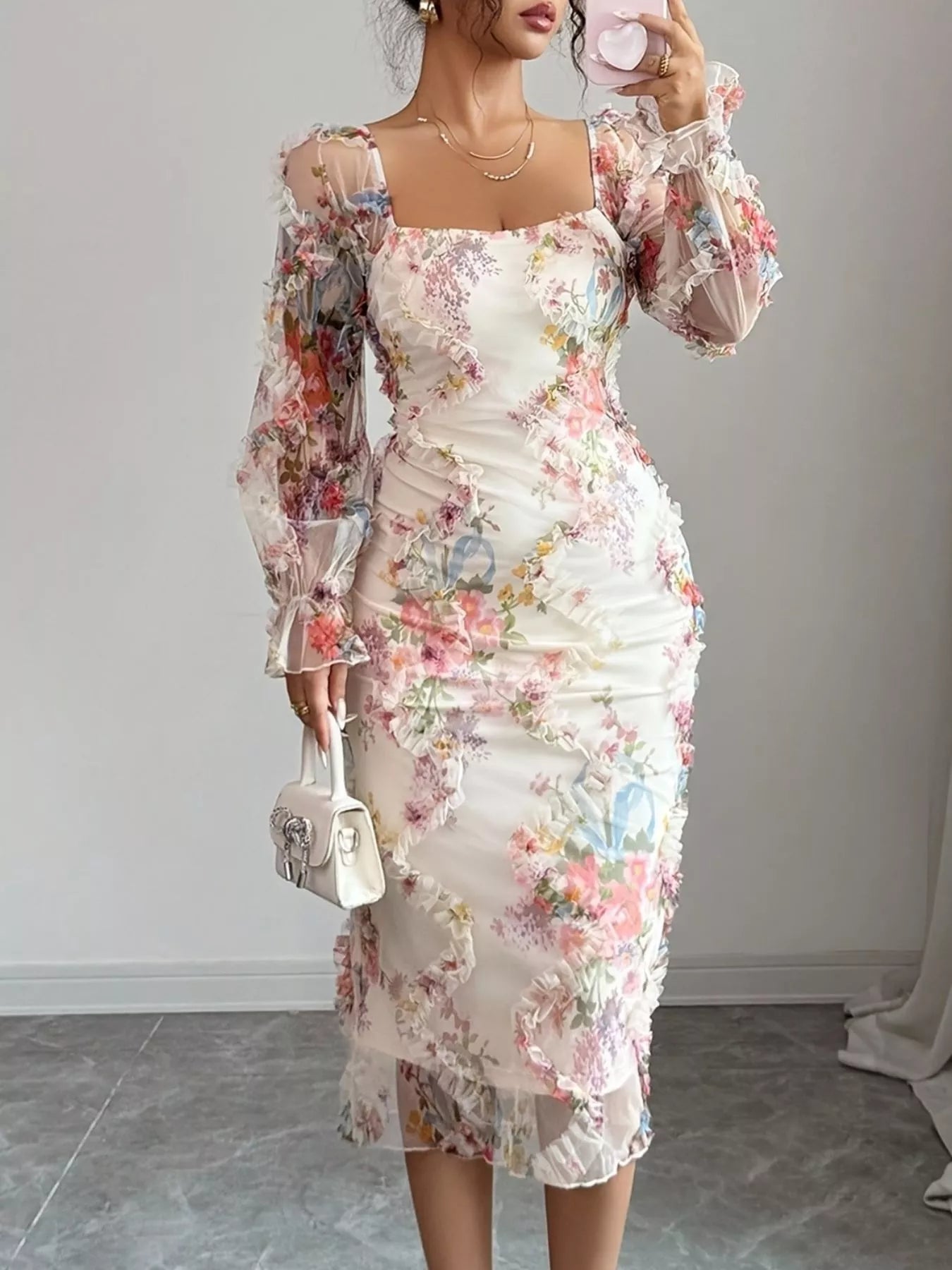 NEWYORKLISTED STYLE COLLECTION: Woman wearing a floral dress with sheer sleeves against a plain background