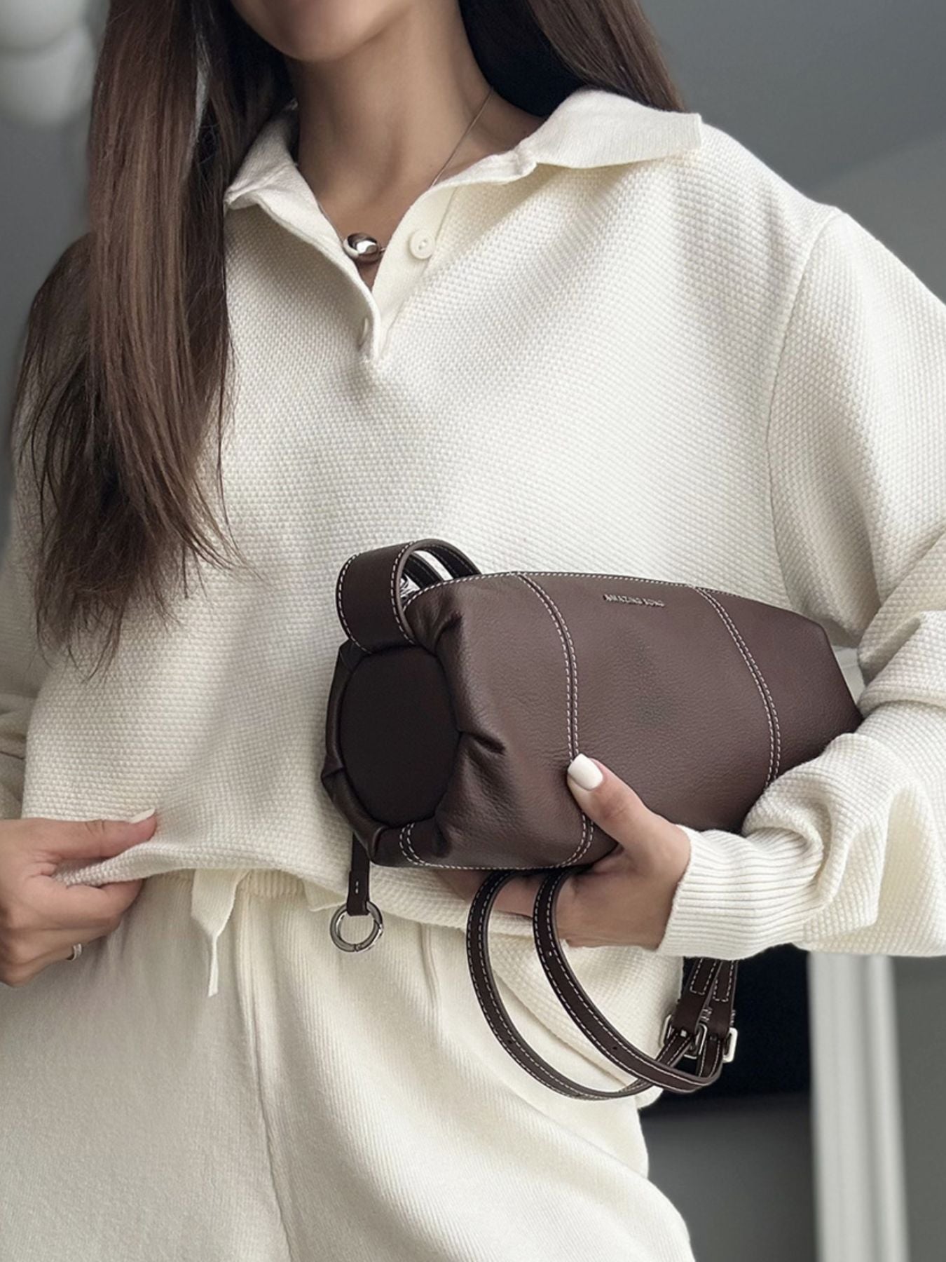 NEWYORKLISTED Comfort Collection: Person holding a brown handbag with a neutral background